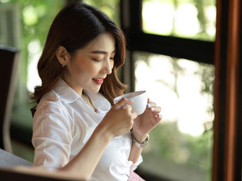 Woman drinking coffee while sitting at cafe