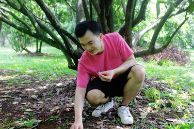 Full length of girl sitting on land in forest