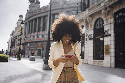Woman using smart phone walking at street