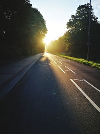 Road amidst trees against sky during sunset