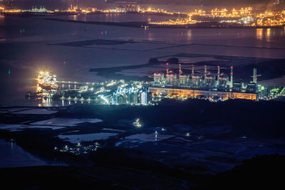 High angle view of illuminated cityscape by sea at night