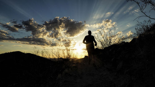 Silhouette man standing on field against sky during sunset