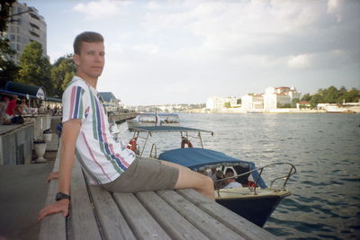 Man sitting on boat in city against sky