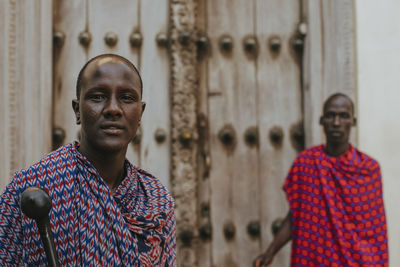 Two masai men standing in front of a traditional door in old town