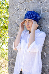 Portrait of young woman standing against tree trunk