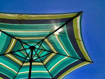 Low angle view of umbrella against clear blue sky