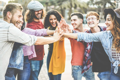 Friends doing high-five standing on footpath