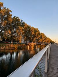 Trees by lake against sky during autumn