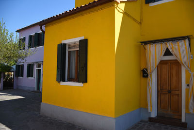 Yellow house by building against sky