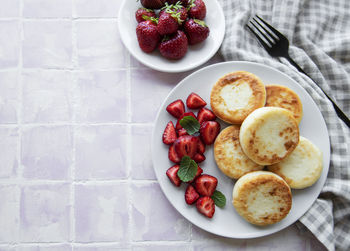 Cottage cheese pancakes, ricotta fritters on ceramic plate with fresh strawberry. 