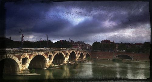 Bridge over river against cloudy sky