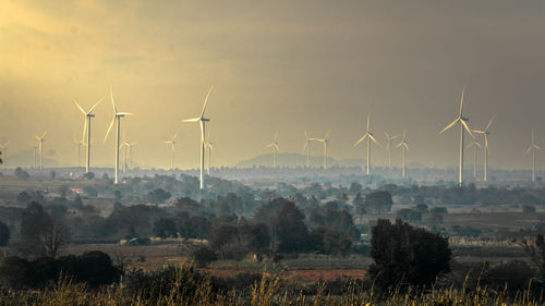 Windmills on land against sky