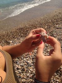 Midsection of man holding pebbles at beach