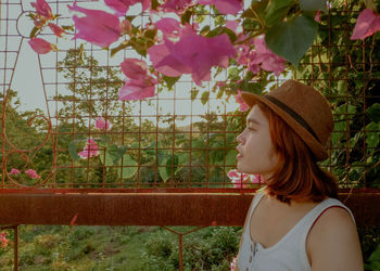 Woman with pink flowers against fence