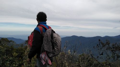 Rear view of man looking at mountains against sky