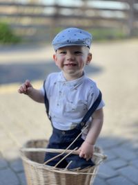 Boy wearing beret standing in wicker basket wearing shorts with suspenders dynamism emotion retro 