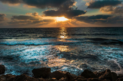 Scenic view of sea against cloudy sky during sunset