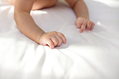 Cropped image of baby lying on bed at home