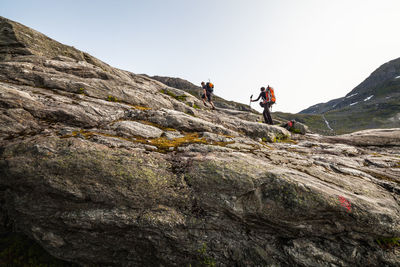 Low angle view of people hiking against sky