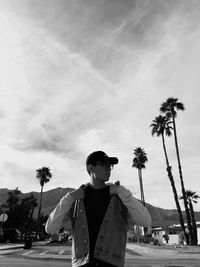 Man standing on street against palm tree