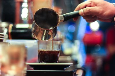 Close-up of hand pouring coffee in cafe