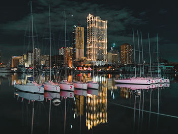 Sailboats moored on illuminated building against sky at night