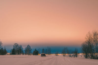 Road by trees against sky during winter