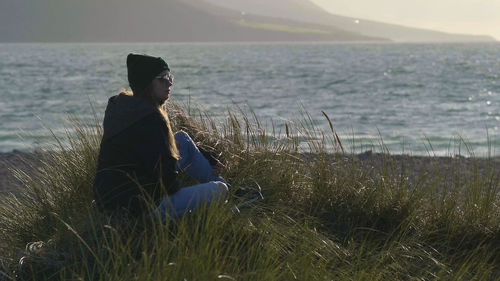 Man sitting on grass by sea