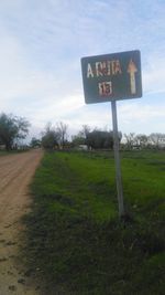 Information sign on field against sky