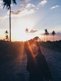 Portrait of young woman standing against sky during sunset