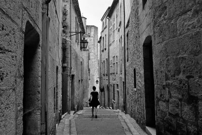 Rear view full length of woman walking in alley