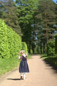 Full length of woman standing on footpath amidst trees