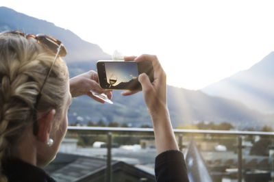 Midsection of man using mobile phone against sky