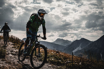 People riding bicycle on mountain against sky