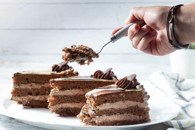 Hand holding a slice of delicious chocolate cake with fluffy cocoa sponge and marble effect icing.