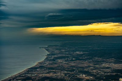 High angle view of coastline and clouds against sun