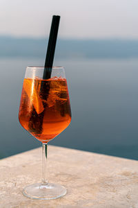 Aperol spritz cocktail on the seaside with orange and ice and straw 