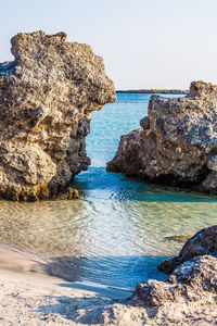 Rock formation on beach against clear sky