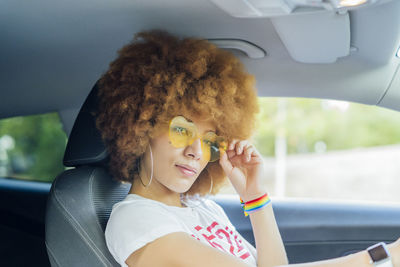 Woman with afro hair putting her glasses in her white car