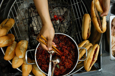 Directly above view of hands stuffing stewed pork into a banhmi in hue city night market, vietnam