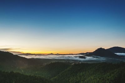 Scenic view of silhouette mountains against clear sky during sunset