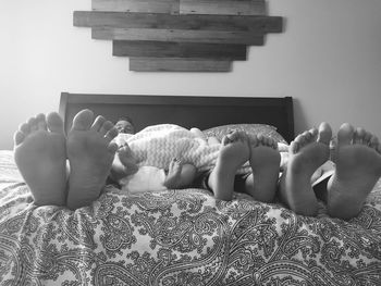 Low section of people relaxing on bed at home
