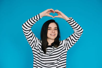 Portrait of woman standing against blue background