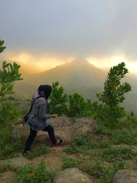 Rear view of woman looking at mountain against sky