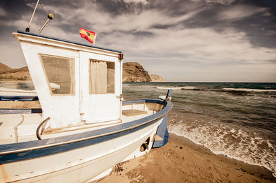 Boat moored on beach against sky