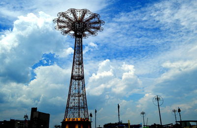 Low angle view of ferris wheel against cloudy sky in coney island.