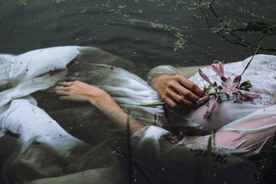 High angle view of woman hand by flowering plants