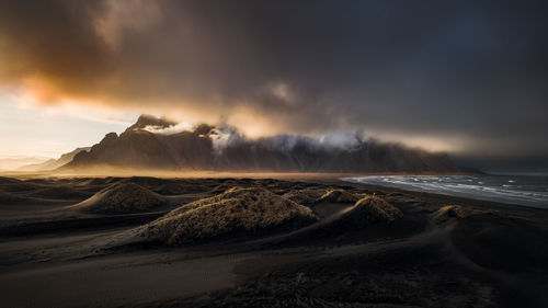 Panoramic sunset view of black sand dunes at stokksnes and cloud-covered mount vestrahorn. iceland. 