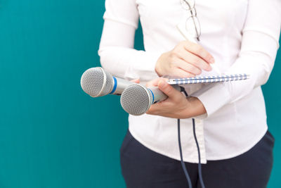 Midsection of female journalist holding microphone