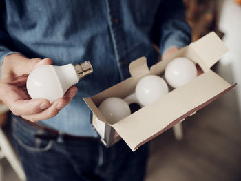 Close-up of man holding a box of led lightbulbs